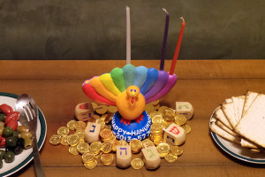 A turkey-shaped Menorah, dubbed a "Menurkey," is surrounded by gelt and dreidls at a 2013 Thanksgivukkah celebration. Creative commons image by Beowabbit